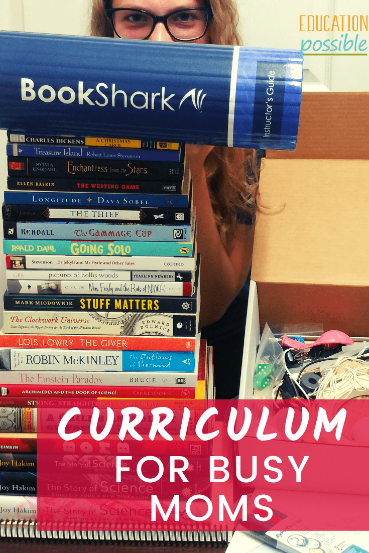 A stack of books that come in BookShark's level 8 curriculum, box of science supplies, laminated folded map, teen girl peeking over stack.