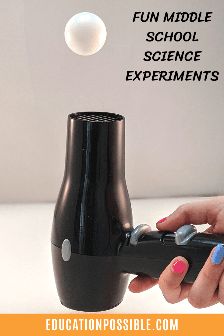 Older girl's hand holding black hairdryer, blowing a white ping pong ball in the air. Black text on the image reads Fun Middle School Science Experiments.
