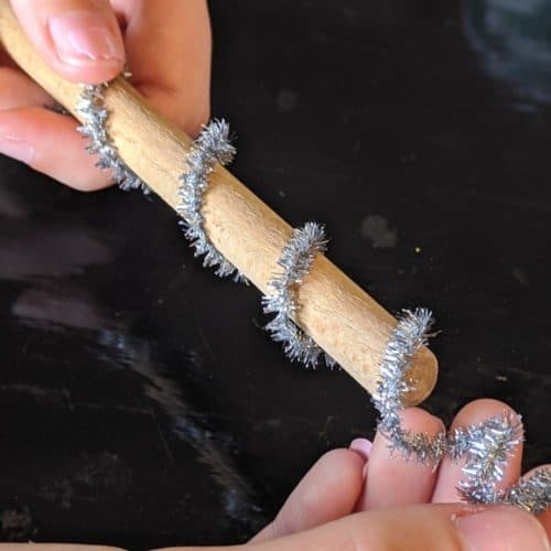 Wrapping silver pipe cleaner around wooden spoon handle