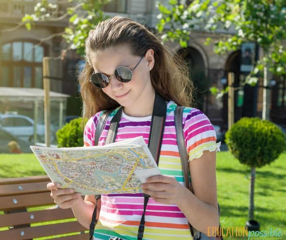 Teen girl with camera around her neck reading a map to navigate her trip.