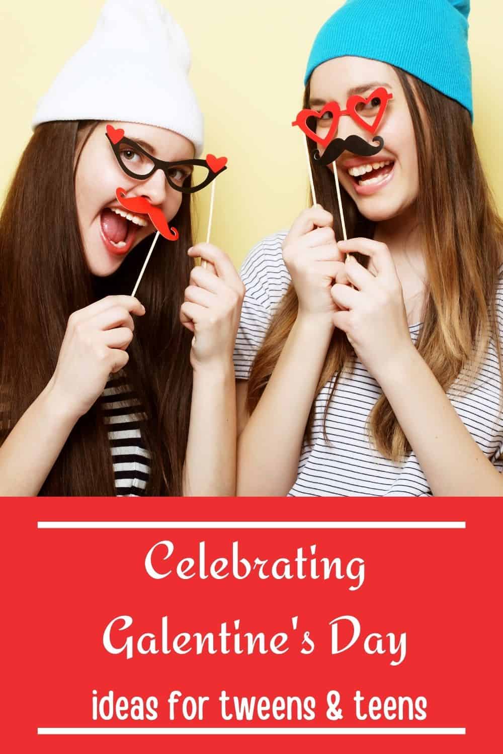 Two teen girls holding up Valentine themed photo booth props.