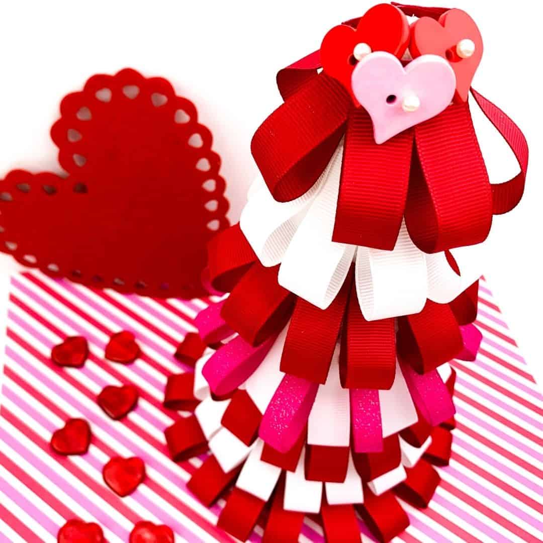 Plastic hearts pinned to the top of a Valentine's Day ribbon tree craft.