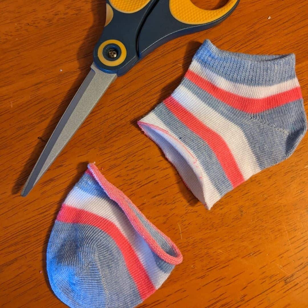 Scissors next to a small striped sock with the toe portion cut off.