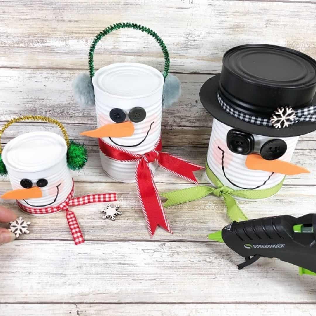 A DIY craft - three tin can snowmen. Adding small wooden snowflakes to them.