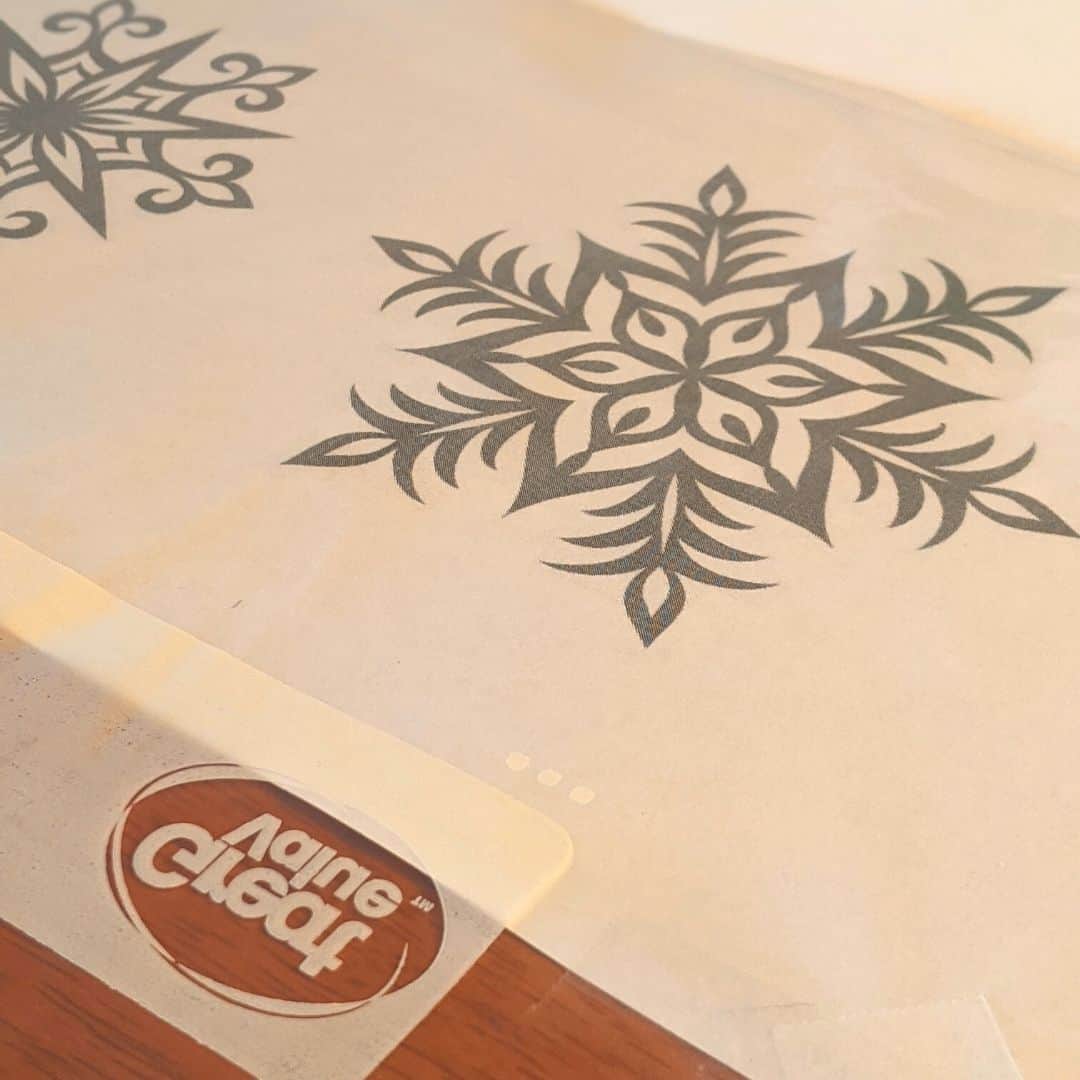 Snowflake template taped to table with plastic bag over it.