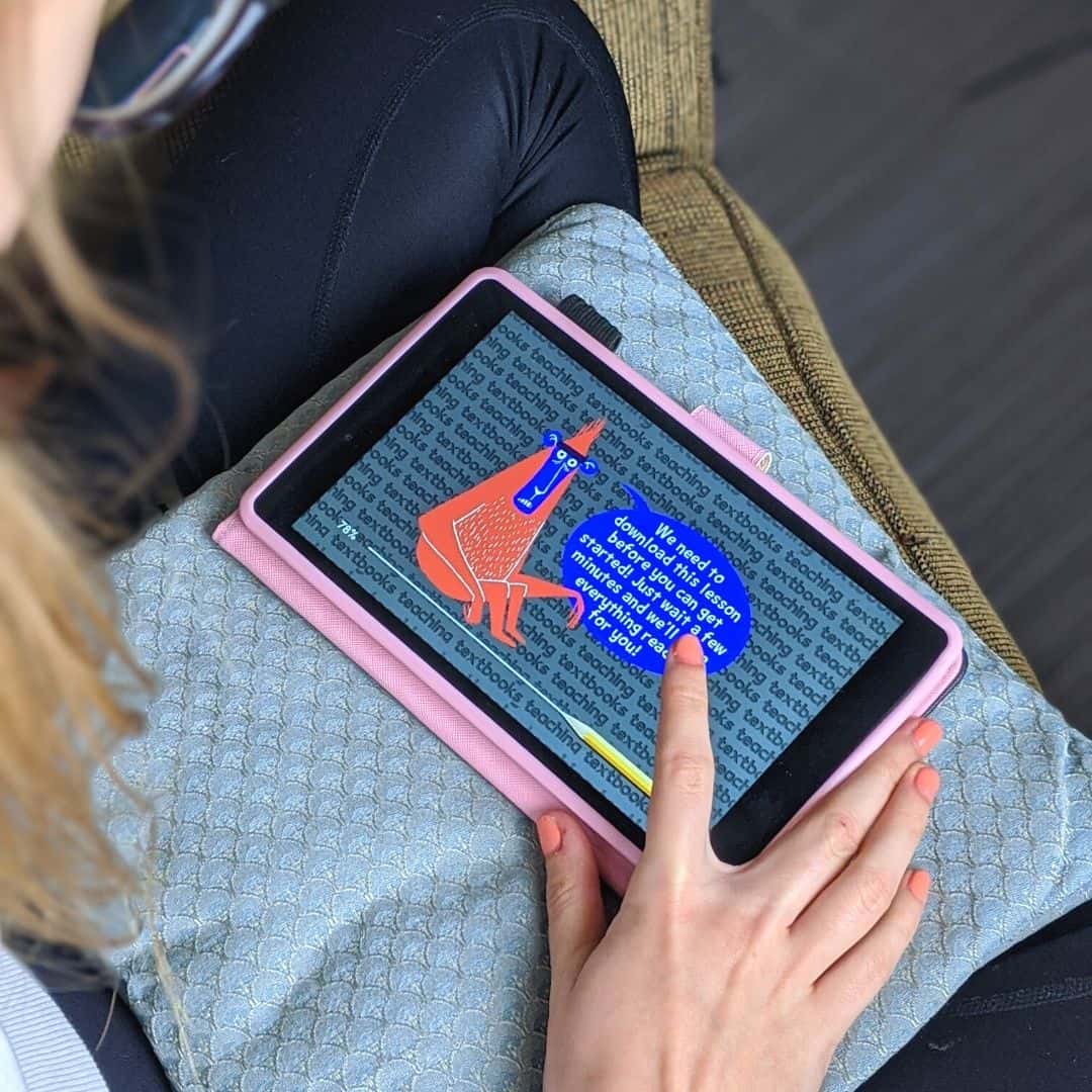 Girl working on math on a tablet in a pink case.