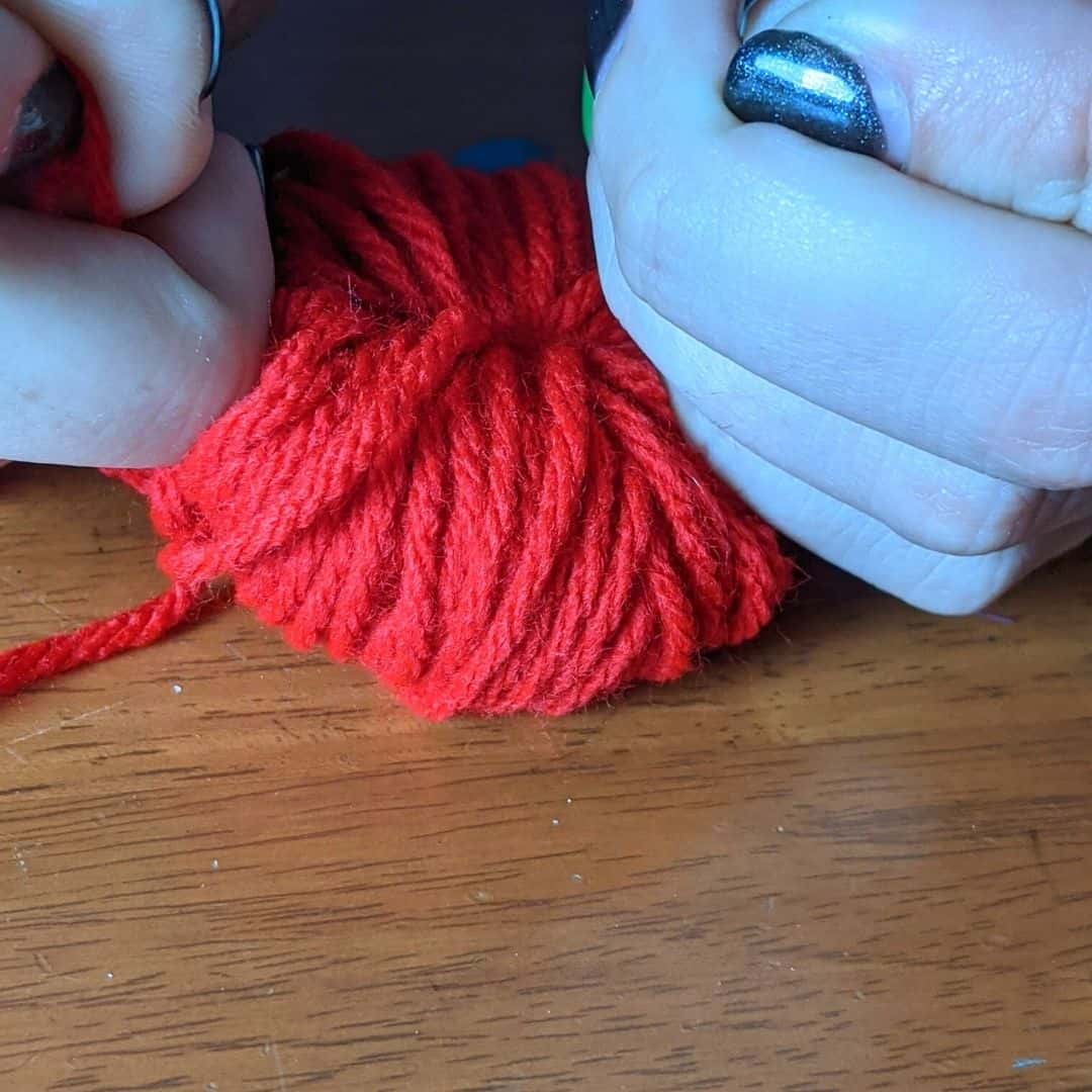 Girl tying yarn to make a pom-pom