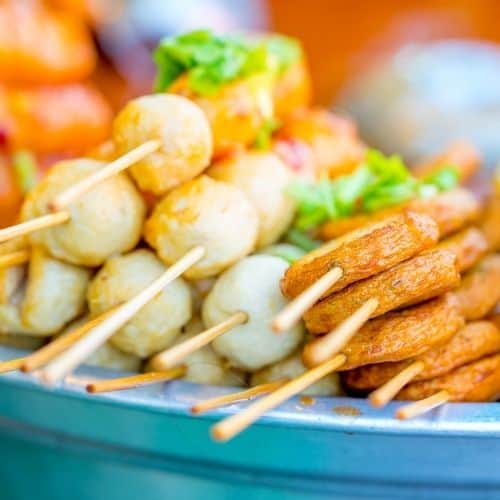 Blue plate covered with food on a stick - green grapes and potato rounds.