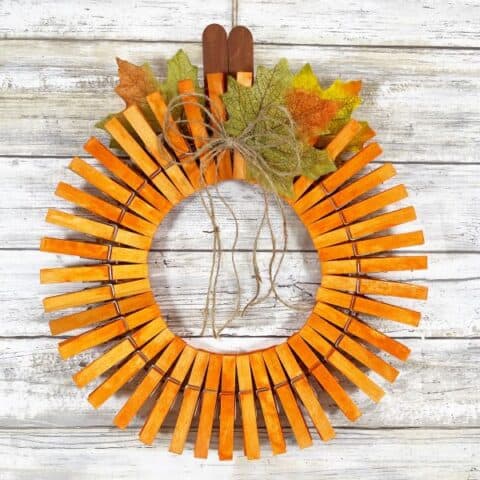 A DIY pumpkin wreath made out of clothespins painted orange