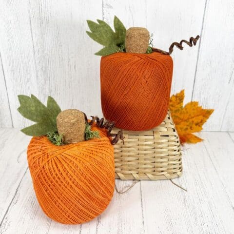 Two pumpkins made from orange colored crochet thread balls.