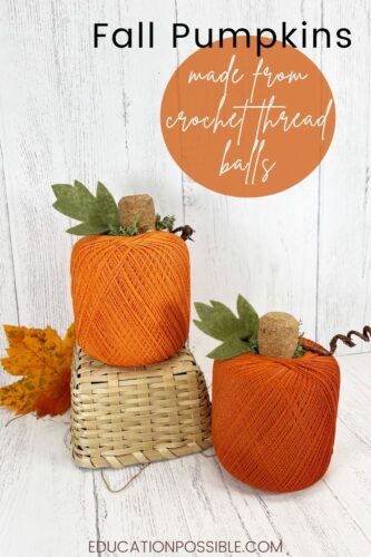 Two orange crochet ball pumpkins on a white table, one sitting on a small wicker basket.
