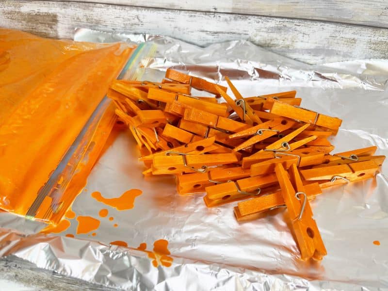 Taking orange painted clothespins out of the bag and putting them on a foil lined tray