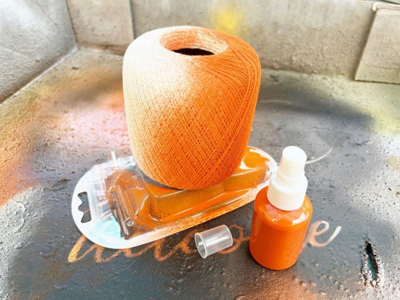 Spraying a white thread ball orange