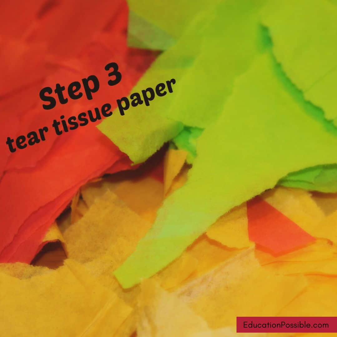 Ripped pieces of red, lime green, and yellow tissue paper in a pile.