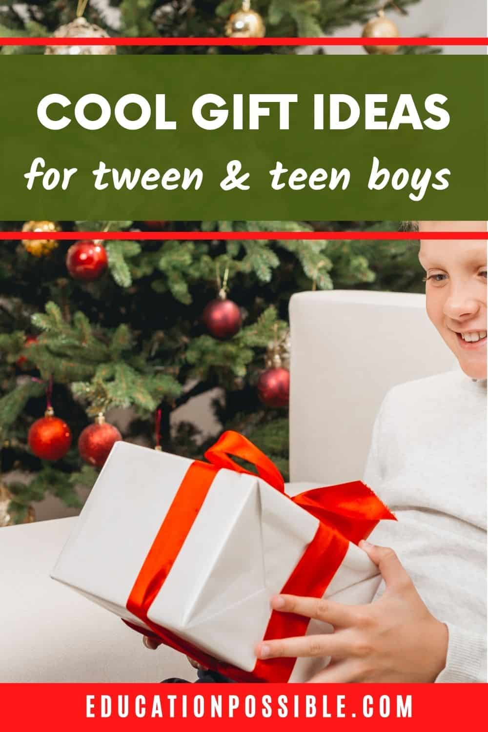 Tween boy sitting on a white couch next to a Christmas tree, holding a gift wrapped with white paper and red bow.