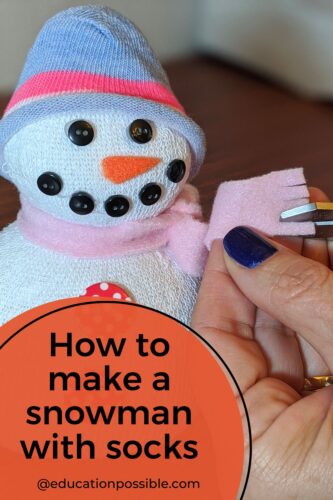 Homemade sock snowman with woman cutting fringe in it's pink fleece scarf.
