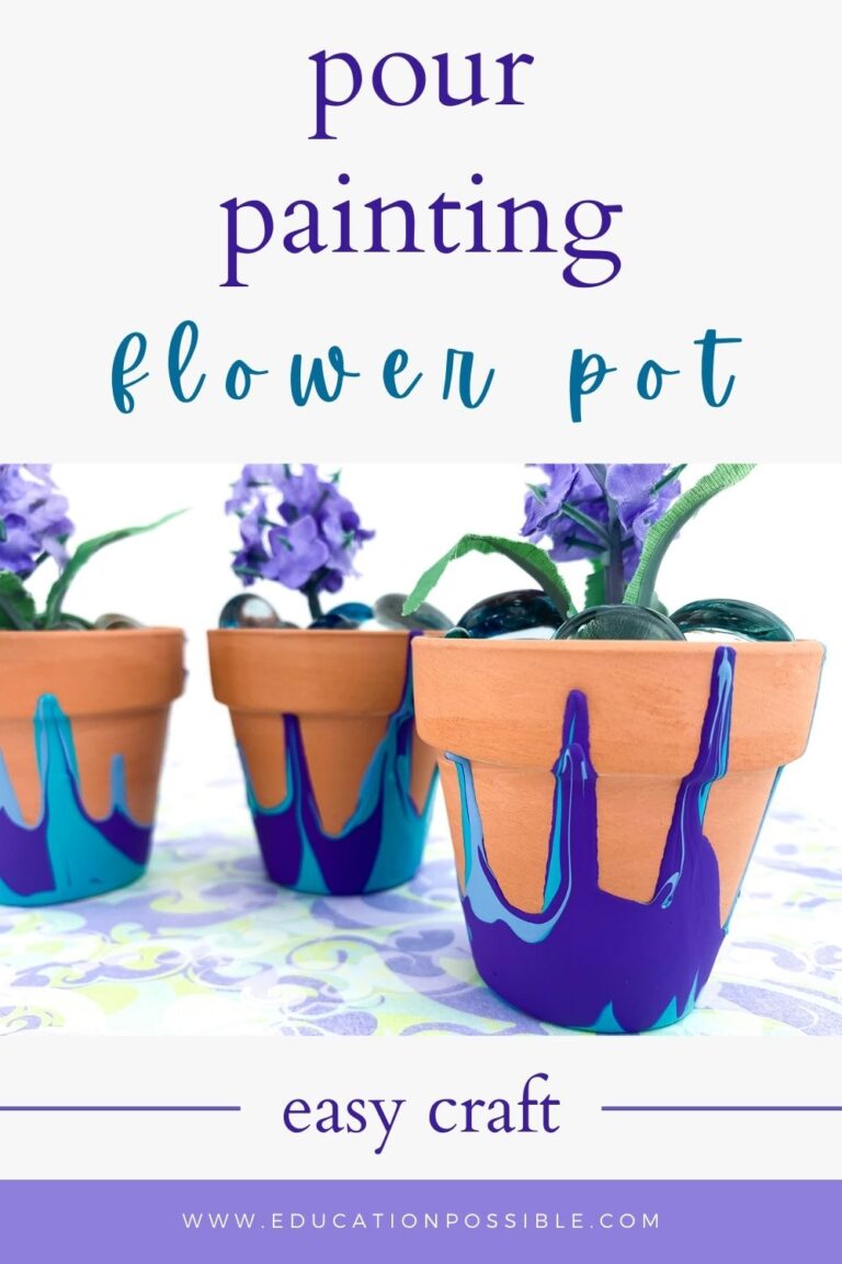 Three DIY pour painted flower pots on a purple/green print fabric. Purple and blue paint on the pots. Filled with light purple silk flower and glass beads.