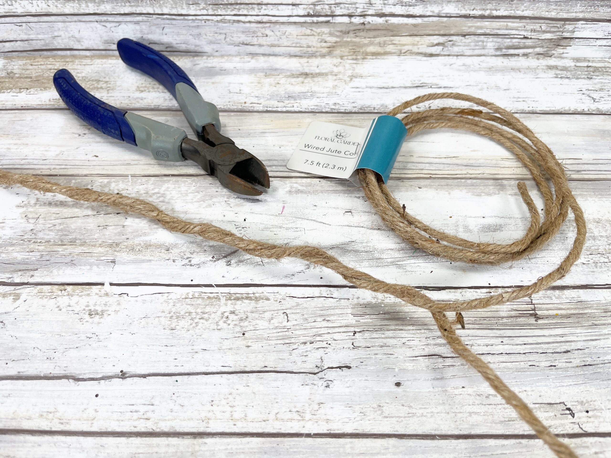 Wired jute cord and wire cutters sitting on a whitewashed table.