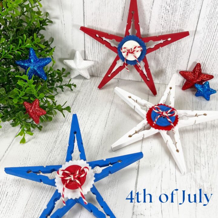Red, white and blue clothespin stars (craft) with a felt circle, button, and twine bow in the middle laying on a white washed table.