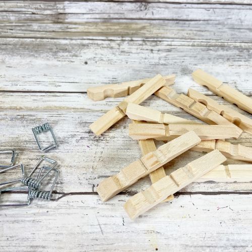 Wooden clothespins and metal springs in piles on a worn white table.