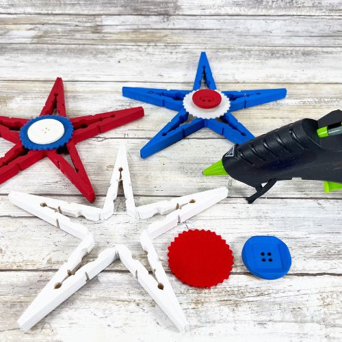 Red, white and blue clothespin stars craft. Glue gun being used to put a button and felt circle to the star.